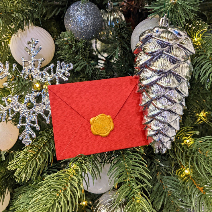 scavenger hunt clue in a red envelope with gold seal in a Chrsitmastree